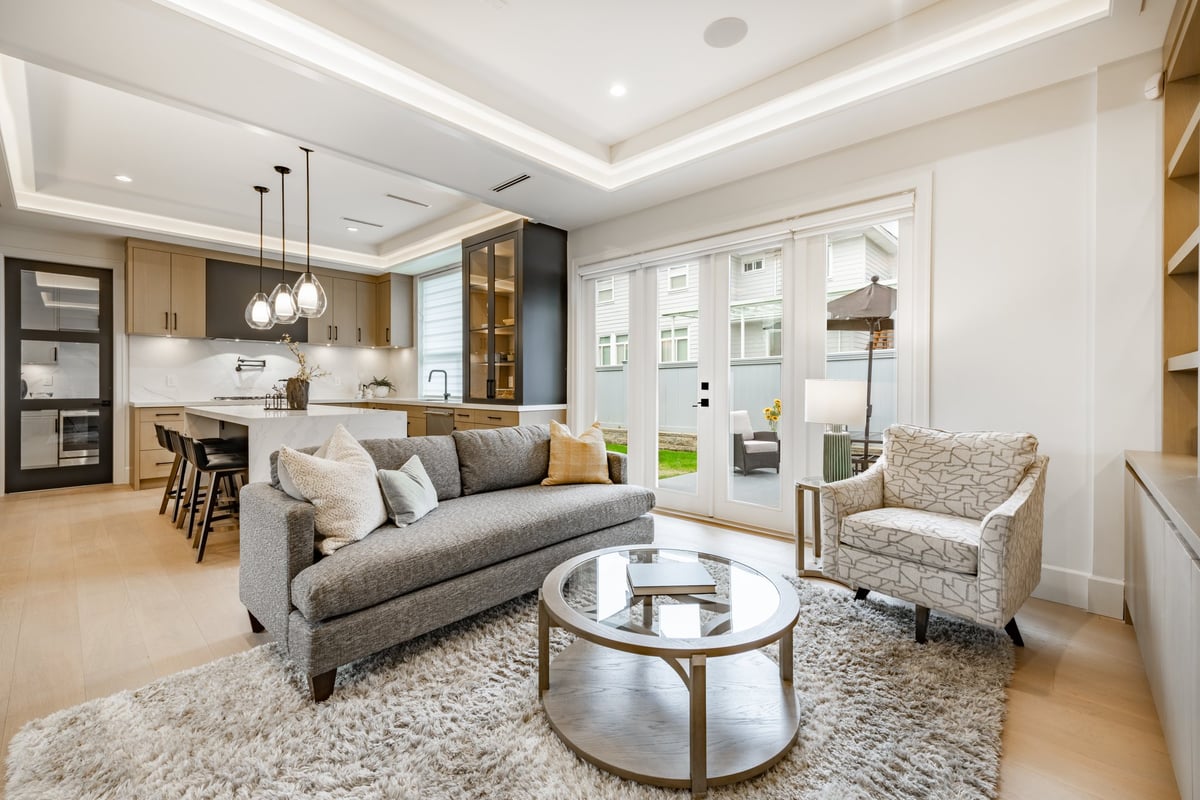 Spacious living room in a newly constructed home, professionally staged with a grey sofa, area rug and built-in shelving